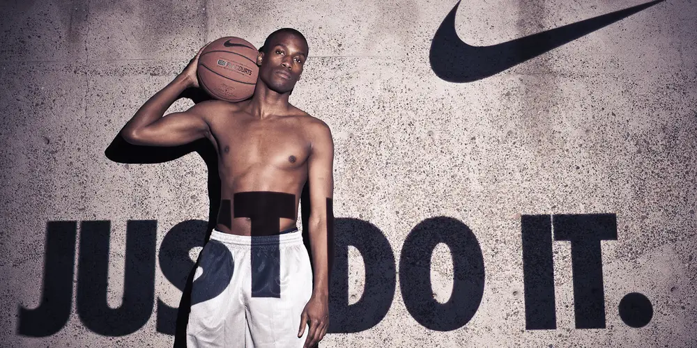 A Nike Just Do It ad. We see the top half of A shirtless man holding a basketball awkwardly on his shoulder, a neutral expression on his face.